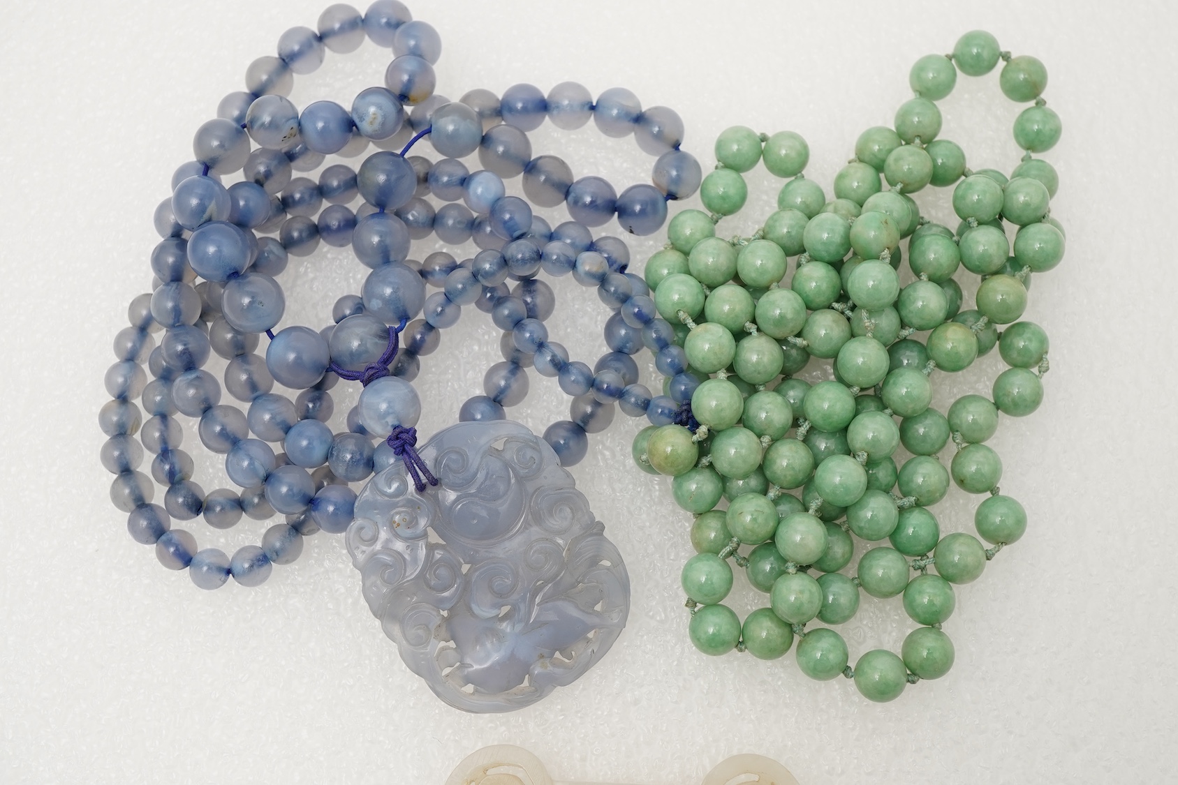 A Chinese jade ‘spirit lock’ plaque, a jadeite bead necklace and a blue quartz bead necklace, 20th century